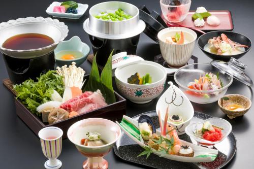 a table topped with bowls and plates of food at Fujikawaguchiko Onsen Konanso in Fujikawaguchiko