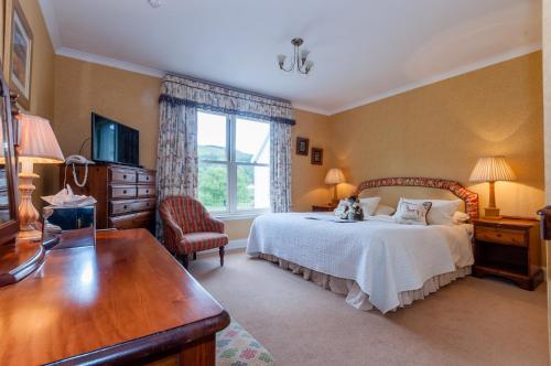 a bedroom with a bed and a desk and a television at Kilcamb Lodge Hotel in Strontian