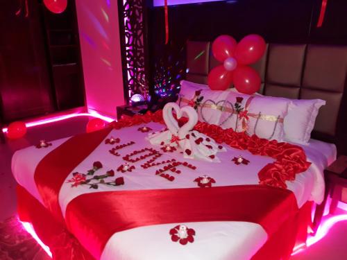 a red and white bed with a heart and balloons at Park Jizan Hotel in Jazan