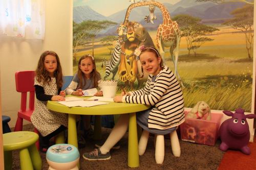 three girls sitting at a table in front of a mural at Stacklerhof in Neustift im Stubaital