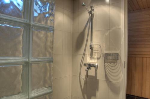a shower with a hose in a tiled bathroom at Kullasmarina Holiday Villas in Padasjoki