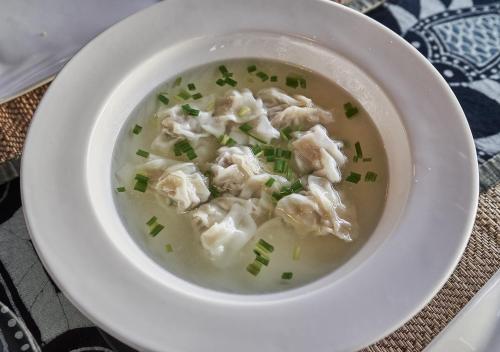 a bowl of wonton soup with dumplings and green onions at Yangshuo Village Inn Boutique Hotel in Yangshuo
