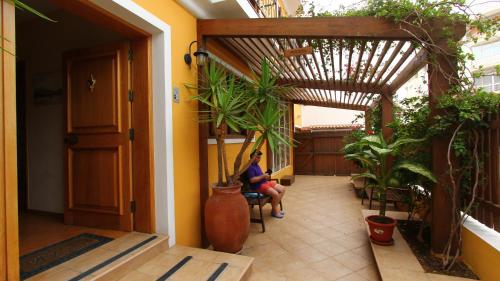 a woman sitting in a chair in a hallway with plants at Kira's Boutique Hotel in Mindelo