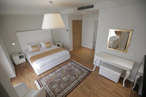 Hotel Bulqiza في Bulqizë: غرفة نوم بيضاء مع سرير ومرآة