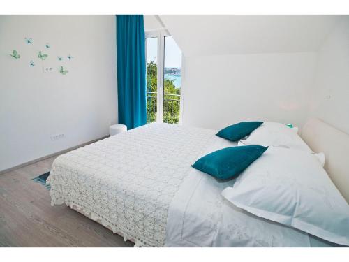 une chambre avec un lit avec des oreillers bleus et une fenêtre dans l'établissement Apartment Splendid Marjan, à Split