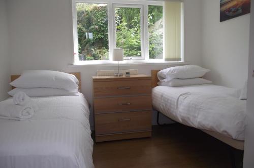 ブリクサムにあるBrixham Harbour Views Houseのベッドルーム1室(ベッド2台付)、ドレッサー(窓付)