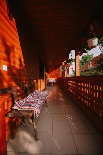 a bench with a striped blanket sitting on a porch at Bosnyák Panzió in Odorheiu Secuiesc