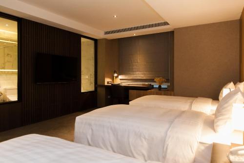 a hotel room with two beds and a desk at Hotel East Taipei in Taipei