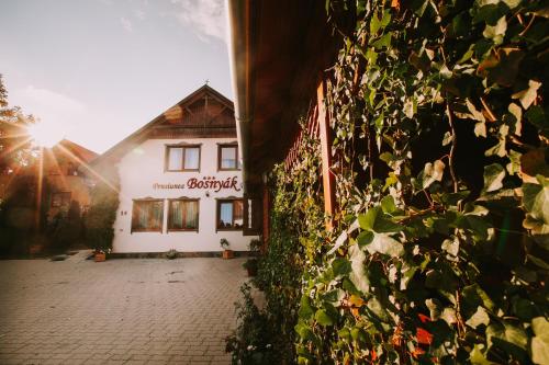 a building with a ivy covered wall next to a building at Bosnyák Panzió in Odorheiu Secuiesc