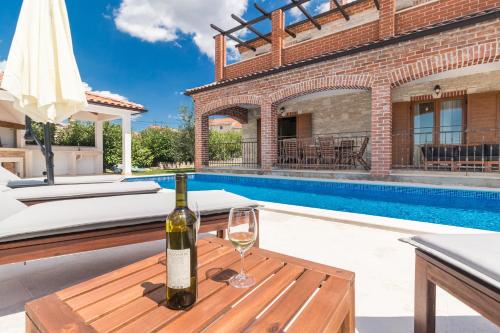 a bottle of wine on a wooden table next to a pool at Villa Ingrid in Poreč