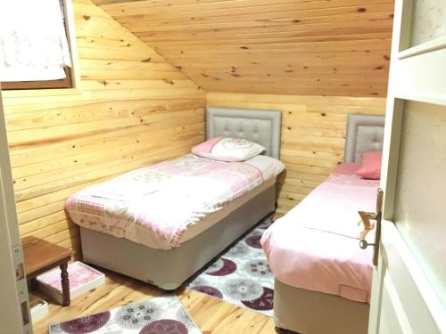 two beds in a room with wooden walls at Caykara Uzungol Bungalow in Uzungol