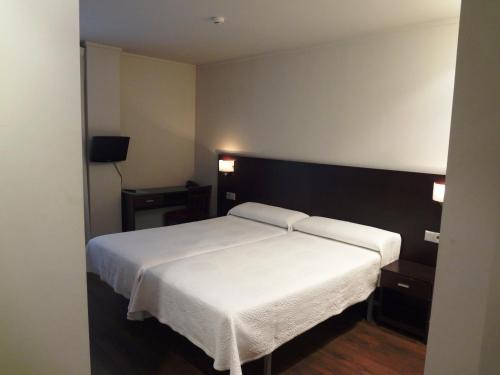 sypialnia z białym łóżkiem i 2 szafkami nocnymi w obiekcie Hotel Irixo w mieście Ourense