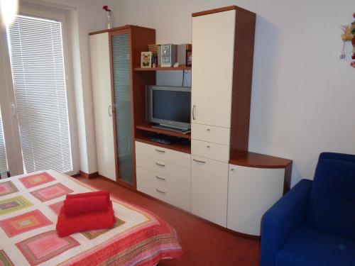 um quarto com uma televisão e uma cama com uma almofada vermelha em Apartment Maja Moravske Toplice em Moravske Toplice