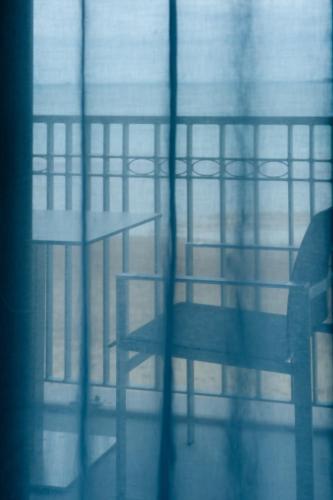 a person sitting on a bench through a window at Hôtel Le Nouveau Monde in Saint Malo