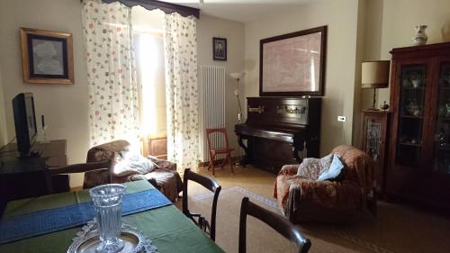 a living room with a table and chairs and a piano at Casa Vacanze Piazza Apartment 2 in SantʼAndrea di Conza