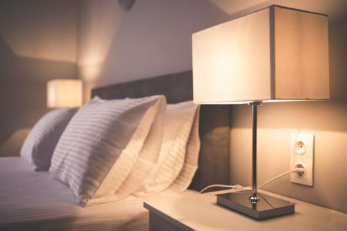 a lamp on a table next to a bed with pillows at Teatro Deluxe Rooms in Kato Rodini