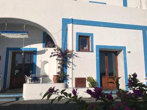 a white building with blue trim and doors and flowers at Da Nino sul mare Filicudi in Filicudi