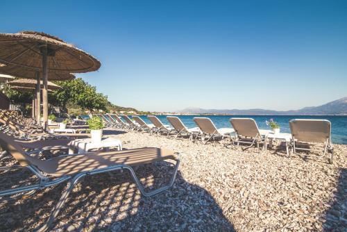 a row of chairs and an umbrella on a beach at Teatro Deluxe Rooms in Kato Rodini