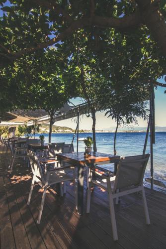 a table and chairs on a deck with the beach at Teatro Deluxe Rooms in Kato Rodini