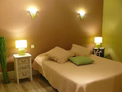 a bedroom with a bed with two lights on the wall at Hôtel du Commerce in Semur-en-Auxois