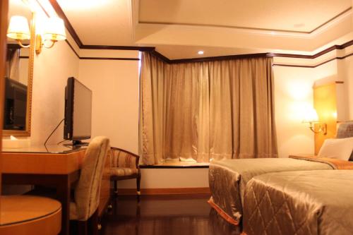 a hotel room with two beds and a desk at Beverly Commercial Motel in Luzhu