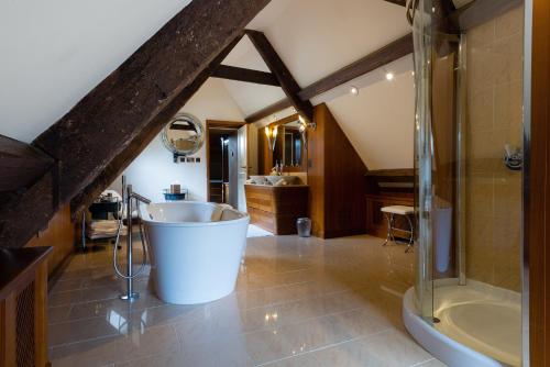 een grote badkamer met een bad en een douche bij Whatley Manor in Malmesbury