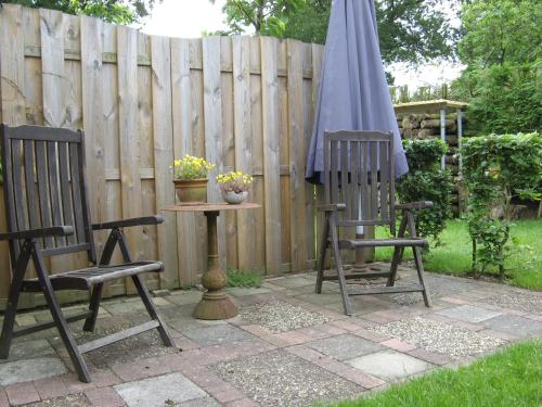 two chairs and a table with an umbrella on a patio at 't Zwaluwennest in Exloo