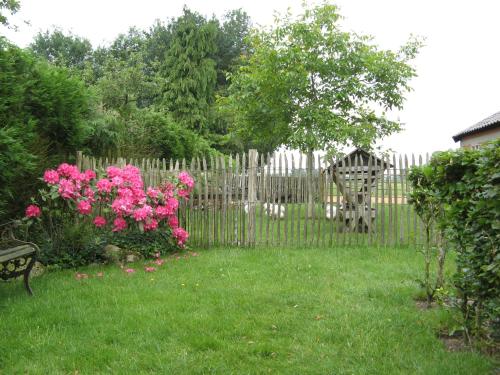 a fence with pink flowers and a bench in a yard at 't Zwaluwennest in Exloo