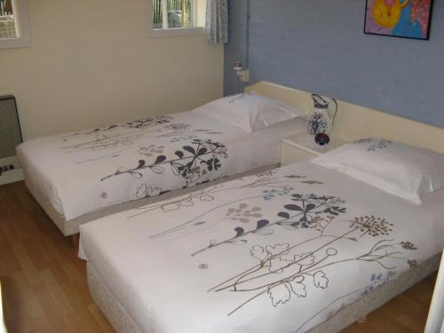 2 Betten in einem Schlafzimmer mit weißer Bettwäsche und Zeichnungen darauf in der Unterkunft 't Zwaluwennest in Exloo
