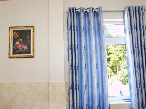 a room with blue curtains and a window at Gia Thanh Phu Quoc Guest House in Phu Quoc