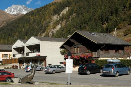 un gran edificio con coches estacionados en un estacionamiento en Auberge des Charmettes, chez Chantal et Yves, en Bourg-Saint-Pierre