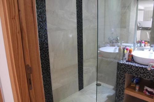 a bathroom with a glass shower and a sink at Paradise Beach in Mansouria