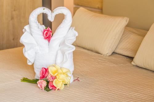 two swan towels and roses on a bed at John's Hotel in Chalkida