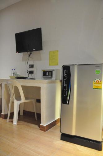 a refrigerator sitting in front of a desk with a television at Banana Resort Sadao in Sadao