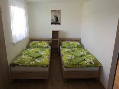two beds in a small room with green comforters at Apartman u Mareka in Sučany