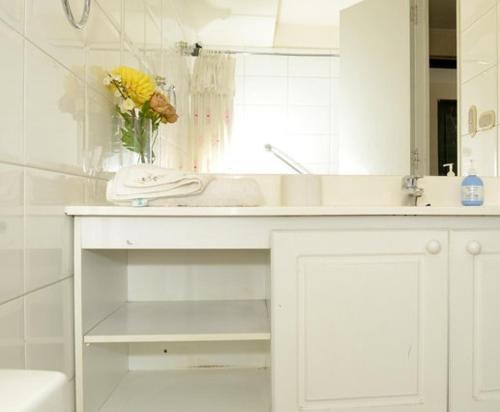 uma casa de banho branca com um lavatório e um espelho em Encomenderos Suites - Apartamentos Amoblados em Santiago