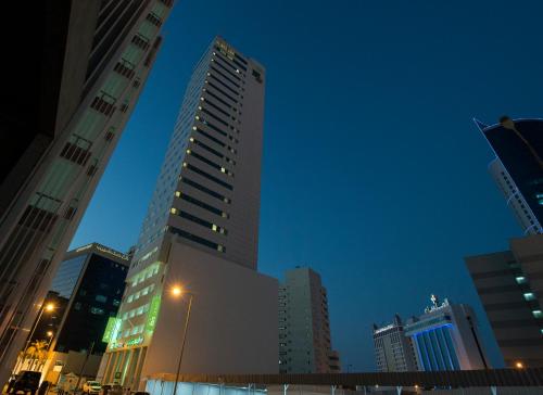 a tall building in a city at night at ibis Styles Manama Diplomatic Area in Manama