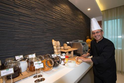 a man in a chefs hat standing next to a counter at ibis Styles Manama Diplomatic Area in Manama
