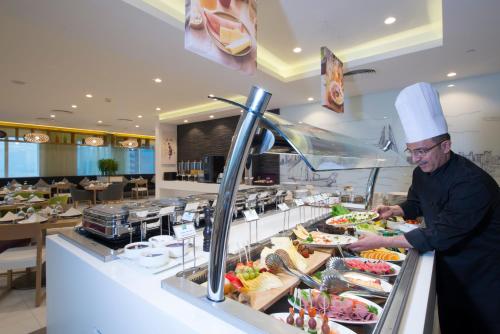 a chef preparing food at a buffet in a restaurant at ibis Styles Manama Diplomatic Area in Manama