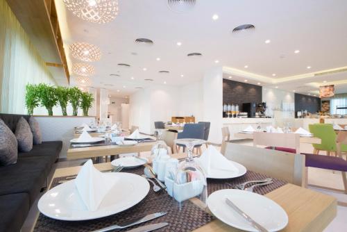 a dining room with white plates and utensils on tables at ibis Styles Manama Diplomatic Area in Manama