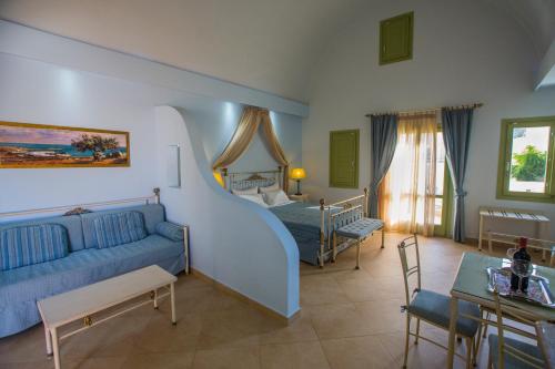 a bedroom with a blue couch and a bed at Anassa Deluxe Suites in Kamari