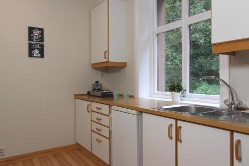 a kitchen with white cabinets and a sink and a window at Slottet Apartments in Tysso
