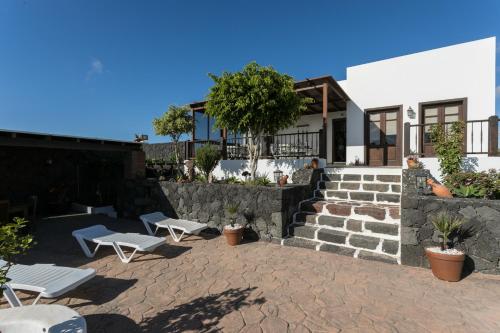 a patio with two white benches and a building at Villa El Jable Lanzarote in Teguise