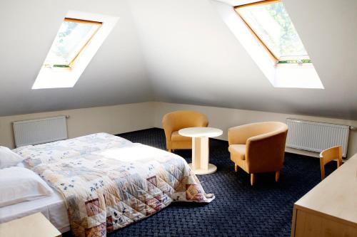 a bedroom with two beds and two chairs and skylights at Domus Hotel in Birštonas