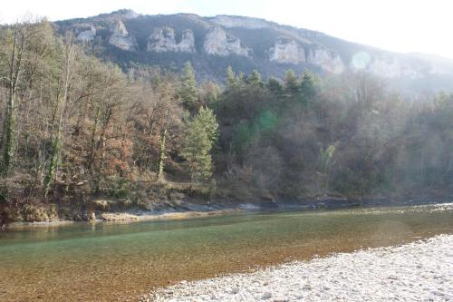 a river with trees and mountains in the background at Les FREJALS in Compeyre