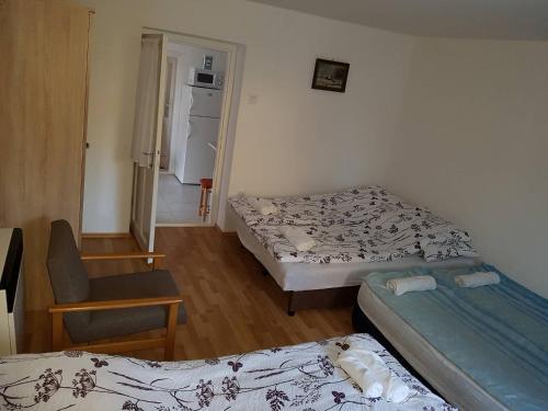 a small room with two beds and a chair at Feszty-fészek Vendégház in Tiszafüred