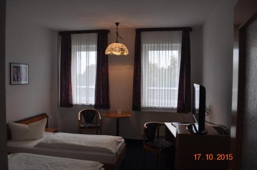 a room with two beds and a desk and windows at Turmhotel Schwedt in Schwedt