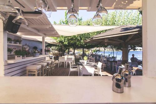 a restaurant with tables and chairs and the ocean at Teatro Deluxe Rooms in Kato Rodini