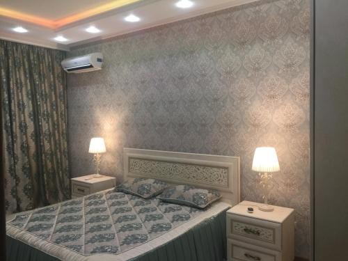 1 dormitorio con 1 cama con 2 mesitas de noche y 2 lámparas en Квартира в 11 микрорайоне, жк. Арай, en Aktobe