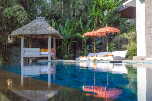 a pool with a gazebo and a bed and an umbrella at The Manipura Luxury Estate and Spa Up to 18 person, fully serviced in Ubud